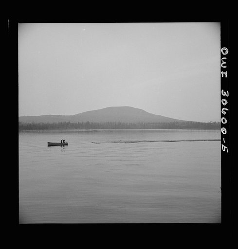 Spring pulpwood drive on the Brown Company timber holdings. The lake steamer's motor boat tows the safety boom to a cove on the shore so it will not be in the way when the steamer picks up the full boom. Later it will be put around the full boom as extra protection for the haul down the lake