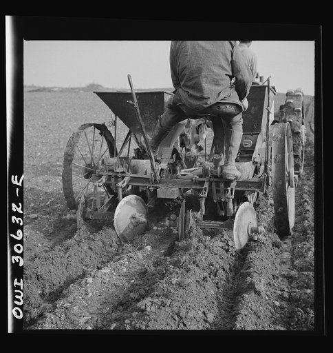 Spring potato planting on the French Acadian farm of Leonard Gagnon. Fort Kent, Aroostook County, Maine. Rear view of two row potato seeding machine