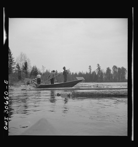 Untitled photo, possibly related to: Spring pulpwood drive on the Brown Company timber holdings in Maine. Woodsmen in a "bateau" opening up on empty boom. These boats are used primarily to clean out logs which have been caught on snags or islands in the large streams and rivers