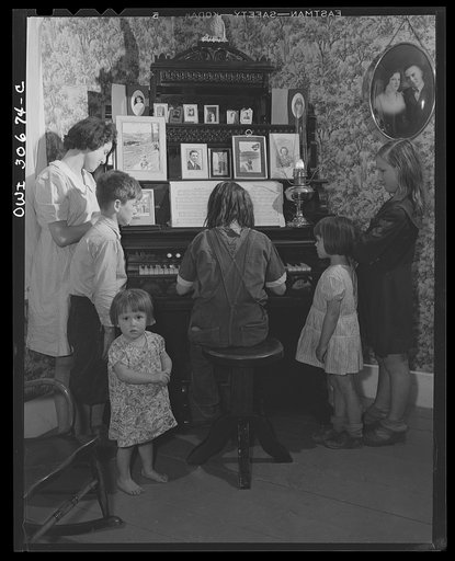 Untitled photo, possibly related to: Fort Kent, Aroostook County, Maine. Spring pototo planting on the French Acadian farm of Leonard Gagnon. The farmer's children aroung the family organ