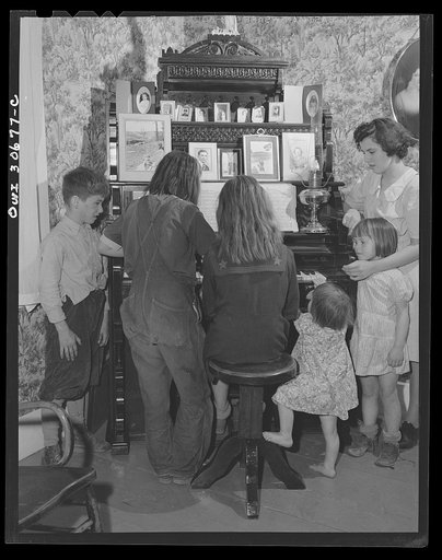 Fort Kent, Aroostook County, Maine. Spring pototo planting on the French Acadian farm of Leonard Gagnon. The farmer's children aroung the family organ