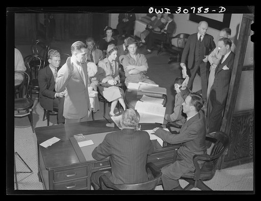 OPA (Office of Price Administration) lawyers holding night hearings for offenders of the pleasure driving regulations. Pittsburgh, Pennsylvania. The man being sworn in has been stopped by policemen, accompanied by an OPA investigator. There was some question as to his reasons for driving, and he was