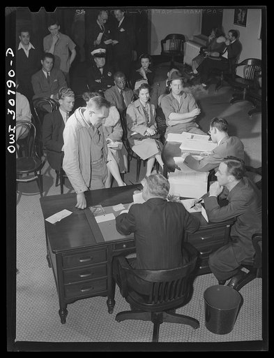 OPA (Office of Price Administration) lawyers holding night hearings for offenders of the pleasure driving regulations. Pittsburgh, Pennsylvania. The man being sworn in has been stopped by policeman, accompanied by an OPA investigator. There was some question as to his reasons for driving, and he was