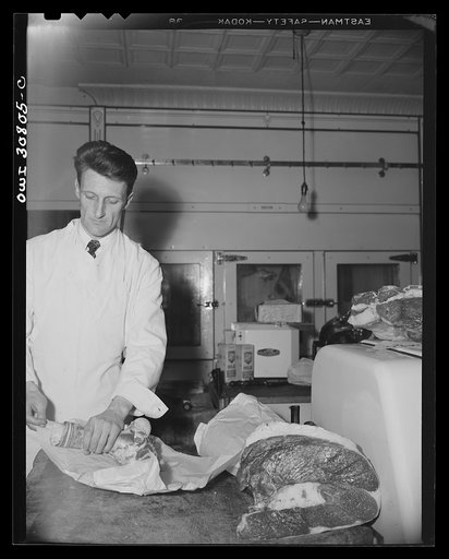 Untitled photo, possibly related to: A patron talking to a butcher over the counter about some meat he is buying. A reconstruction photographed during the filming of "Black Marketing," a motion picture produced by the U.S. Office of War Information (OWI)