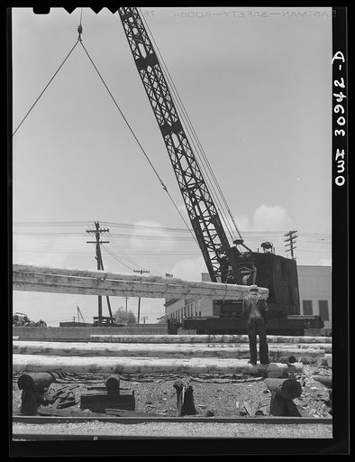 Untitled photo, possibly related to: Beaumont, Texas. Crane picking up properly aged poles which will be treated in vats at the International Creosoting Company