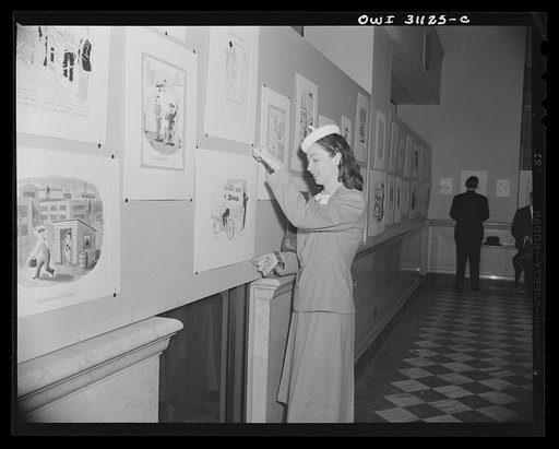 Untitled photo, possibly related to: New York, New York. Margo Cooke, and Louis Priscilla, Chairman of the Committee on War Cartoons of the American Society of Magazine Cartoons, discussing their contribution to an exhibition of cartoons concerning lost hours in war production, sponsored by the OWI 