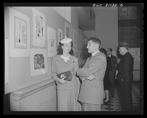 New York, New York. Margo Cooke, and Louis Priscilla, Chairman of the Committee on War Cartoons of the American Society of Magazine Cartoons, discussing their contribution to an exhibition of cartoons concerning lost hours in war production, sponsored by the OWI (Office of War Information)