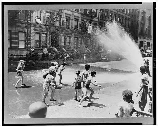 New York, New York. Children escape the heat of the East Side by using fire hydrant as a shower bath