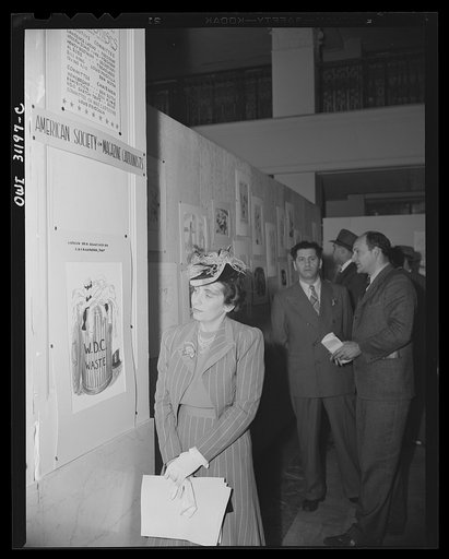 New York, New York. Miss Anna Rosenberg of the War Manpower Commission, at the exhibition of cartoons concerning lost hours in war production, sponsored by the Office of War Information. She is looking at a cartoon, autographed by Mayor La Guardia of New York City, who submitted the idea for this il
