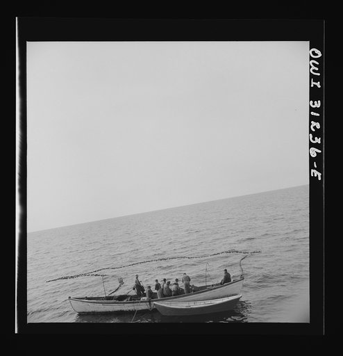 Untitled photo, possibly related to: On board the fishing boat Alden, out of Gloucester, Massachusetts. Fishermen pulling in their net, in which they hope to have trapped a school of mackerel. The big boat stands by ready to go alongside and receive the catch on her decks