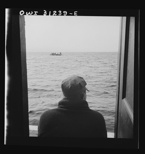 On board the fishing boat Alden, out of Gloucester, Massachusetts. The dories pulling in their nets, seen from the mother ship's cabin window
