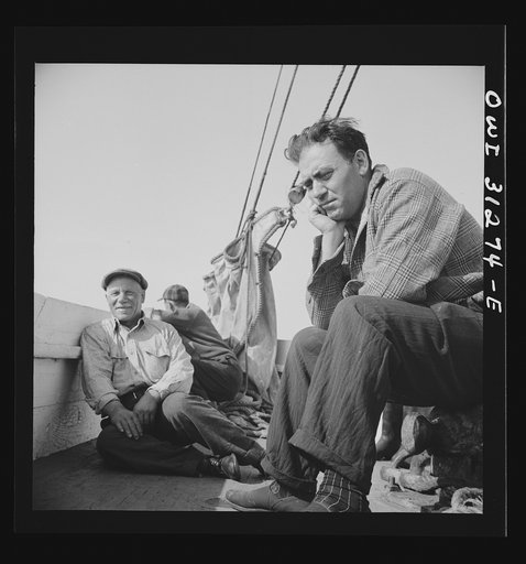 On board the fishing boat Alden out of Gloucester, Massachusetts. Fishermen sitting about the deck on the first morning