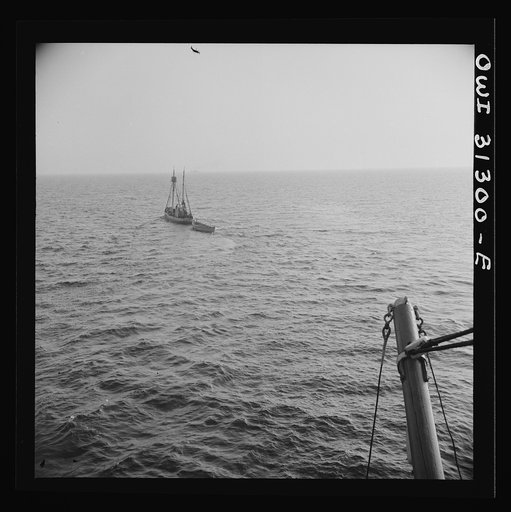 On board the fishing boat Alden out of Gloucester, Massachusetts. Fishing schooner towing a dory off the New England coast