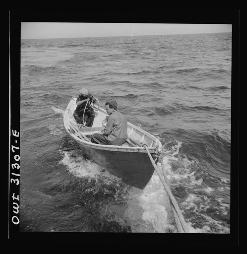 On board the fishing boat Alden, out of Gloucester, Massachusetts. A dory with men, being towed during a mackerel chase