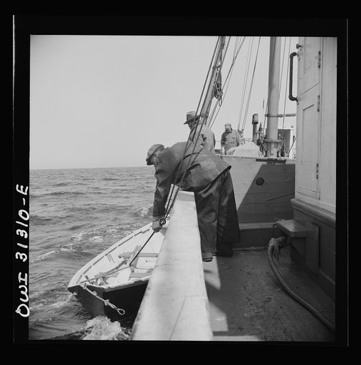 On board the fishing boat Alden, out of Gloucester, Massachusetts. Men letting a dory over the side