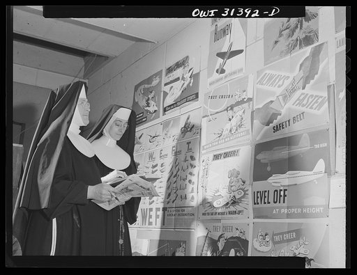 Washington, D.C. Sister Aquinas, "flying nun," and another sister looking at a display of airplane posters. She teaches a Civil aeronautics authority course for instructors, at Catholic University, during the summer