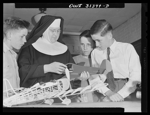Untitled photo, possibly related to: Washington, D.C. Sister Aquinas, "flying nun," applying a little glue to the model P-38 which hangs from the ceiling of her classroom at Catholic University. A veteran of fifteen years' teaching experience, the Sister is giving a summer Civil Aeronautics Authorit