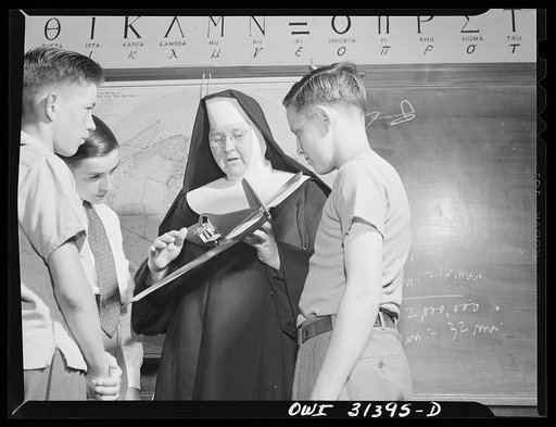 Untitled photo, possibly related to: Washington, D.C. Sister Aquinas, "flying nun," applying a little glue to the model P-38 which hangs from the ceiling of her classroom at Catholic University. A veteran of fifteen years' teaching experience, the Sister is giving a summer Civil Aeronautics Authorit