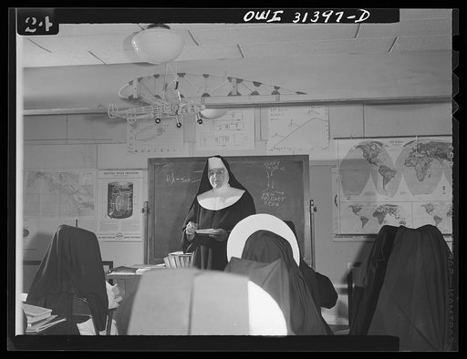 Untitled photo, possibly related to: Washington, D.C. Sister Aquinas, "flying nun," applying a little glue to the model P-38 which hangs from the ceiling of her classroom at Catholic University. A veteran of fifteen years' teaching experience, the Sister is giving a summer Civil Aeronautics Authorit
