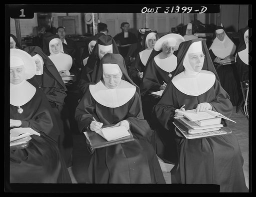 Untitled photo, possibly related to: Washington, D.C. Sister Aquinas, "flying nun," applying a little glue to the model P-38 which hangs from the ceiling of her classroom at Catholic University. A veteran of fifteen years' teaching experience, the Sister is giving a summer Civil Aeronautics Authorit