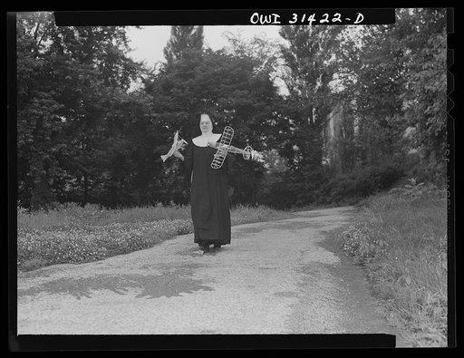Untitled photo, possibly related to: Washington, D.C. Sister Aquinas, "flying nun", with model planes in hands walking toward the aeronautics laboratory at Catholic University where she gives a daily three-hour preflight Civil Aeronautics Authority course for instructors