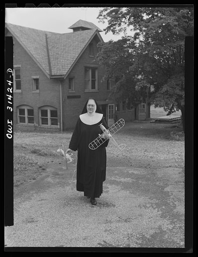 Washington, D.C. Sister Aquinas, "flying nun", with model planes in hands walking toward the aeronautics laboratory at Catholic University where she gives a daily three-hour preflight Civil Aeronautics Authority course for instructors