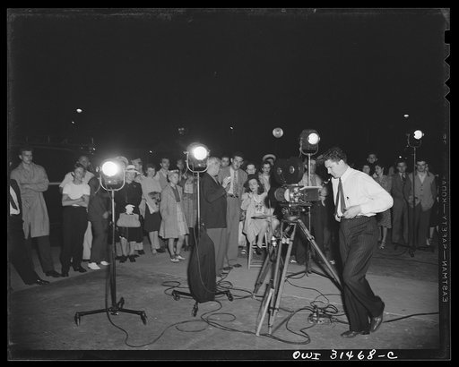 Motion picture men and equipment set up outside a grocery and meat market, used during the filming of "Black Marketing," produced by the U.S. Office of War Information (OWI) and released August 19, 1943