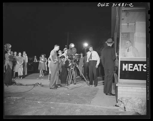 Motion picture men and equipment set up outside a grocery and meat market, used during the filming of "Black Marketing," produced by the U.S. Office of War Information (OWI) and released August 19, 1943