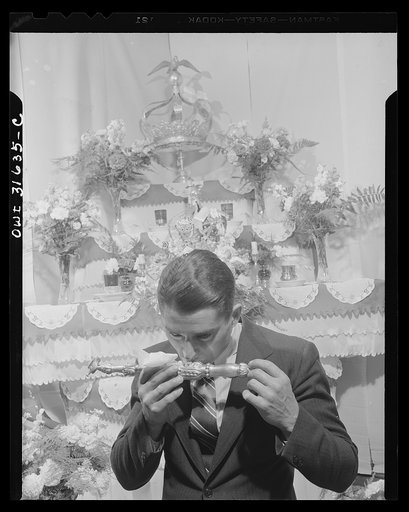 Gloucester, Massachusetts. Frank Domingos kissing a vessel representing remains of a saint, during ceremonies at his father's home, part of the tri-annual fiesta of Pentacost. The celebration--including the chosing of an Imperator, and visiting, eating, drinking, and worship in the home, culminates 