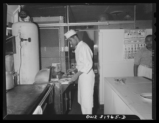 A cook preparing plates in the kitchen of the towboat Ernest T. Weir going down the Ohio River to Cincinnati