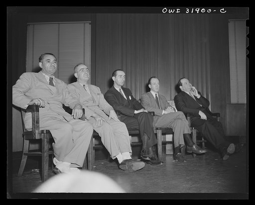 Five men seated in the courtroom(?) during a scene in "Black Marketing," a motion picture produced by the U.S. Office of War Information (OWI)