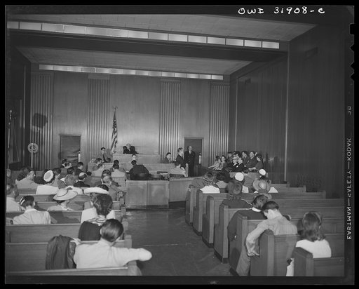 A courtroom scene during a case on illegal meat sales or "black marketing." A reconstruction photographed during the filming of "Black Marketing," a motion picture produced by the U.S. Office of War Information (OWI) and released August 19, 1943