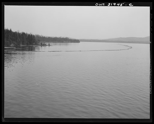 Spring pulpwood drive on the Brown Company timber holdings in Maine. The safety boom, a second boom to provide extra protection when towing the logs, is anchored temporarily while the steamer goes to pick up the full boom it is to tow across Mooselookmeguntic Lake