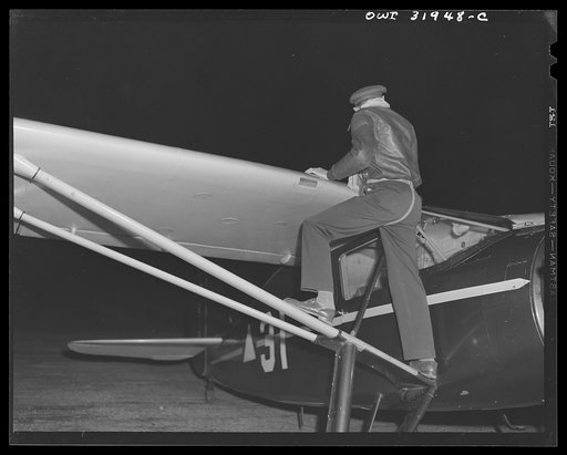 Bar Harbor, Maine. Civil Air Patrol base headquarters of coastal patrol no. 20. Pilot making a routine check on the gas supply before starting out on dawn patrol