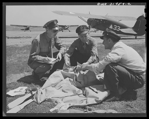 Bar Harbor, Maine. Civil Air Patrol base headquarters of coastal patrol no. 20. Intelligence officer checking safety equipment issued to the pilot and observer of a patrol plane, including rubber boat and life jacket "Mae West," inflatable by carbon dioxide gas catridges; repair kit to mend bullet i