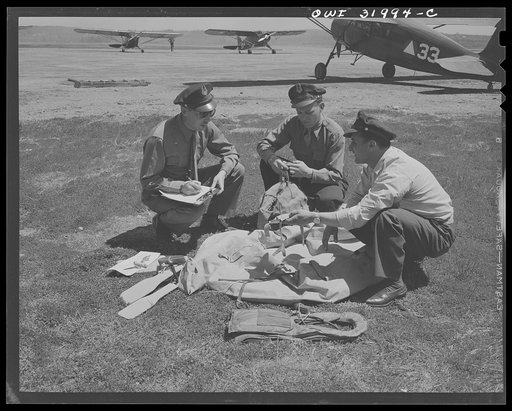 Bar Harbor, Maine. Civil Air Patrol base headquarters of coastal patrol no. 20. Intelligence officer checking safety equipment issued to the pilot and observer of a patrol plane, including rubber boat and life jacket "Mae West," inflatable by carbon dioxide gas cartridges; repair kit to mend bullet 