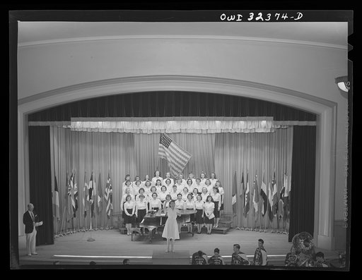 Untitled photo, possibly related to: Oswego, New York. Howard Fast, author of Citizen Tom Paine, addressing the high school. United Nations flags are on the stage during United Nations week
