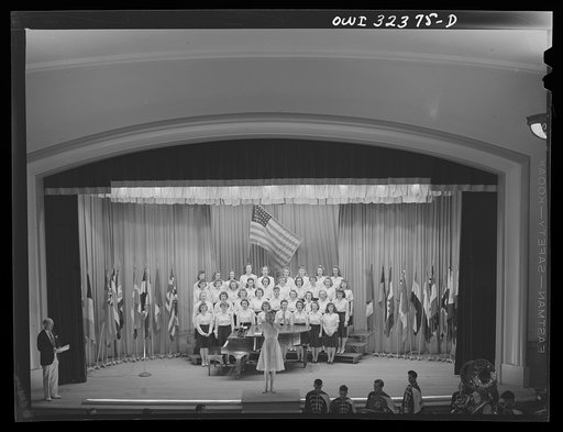 Untitled photo, possibly related to: Oswego, New York. Howard Fast, author of Citizen Tom Paine, addressing the high school. United Nations flags are on the stage during United Nations week