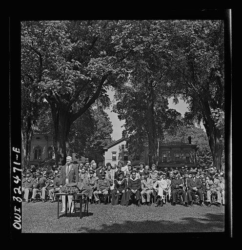Oswego, New York. Howard Fast, author of "Citizen Tom Paine," addressing the high school. United Nations flags are on the stage during United Nations week