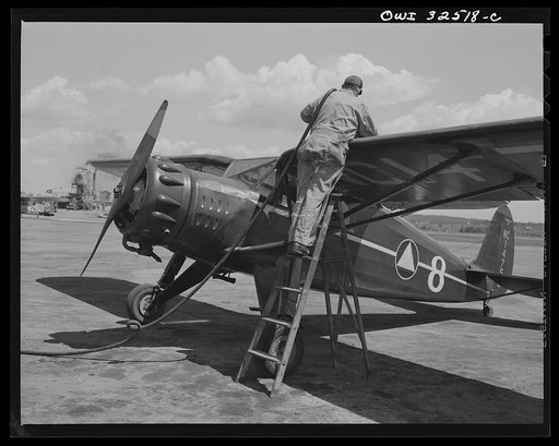 Untitled photo, possibly related to: Bar Harbor, Maine. Civil Air Patrol base headquarters of coastal patrol no. 20. Ground crew mechanic making adjustments on a plane before it takes off