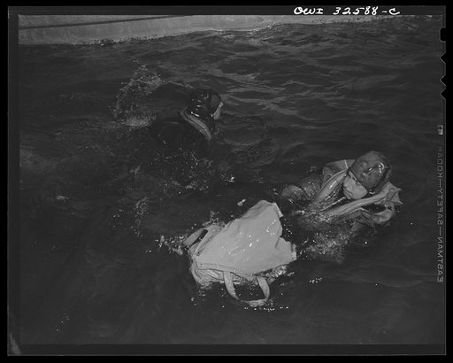 Bar Harbor, Maine. Civil Air Patrol base headquarters of coastal patrol no. 20. A flyer in an all-rubber crash suit testing the use of a rubber boat, which he is extracting from its bag