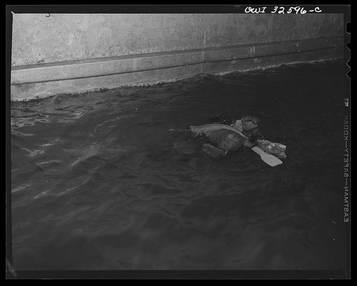 Bar Harbor, Maine. Civil Air Patrol base headquarters of coastal patrol no. 20. A flyer in an all-rubber crash suit testing the use of a rubber boat, which he is extracting from its bag