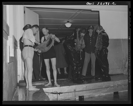 Untitled photo, possibly related to: Bar Harbor, Maine. Civil Air Patrol base headquarters of coastal patrol no. 20. Flyers extracting themselves from all-rubber crash suits after a test in the swimming pool