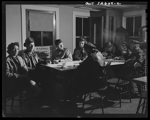 Untitled photo, possibly related to: Bar Harbor, Maine. Civil Air Patrol base headquarters of coastal patrol no. 20. Personnel warming up in the canteen before the dawn patrol. The woman at the near end of the table works in the control tower