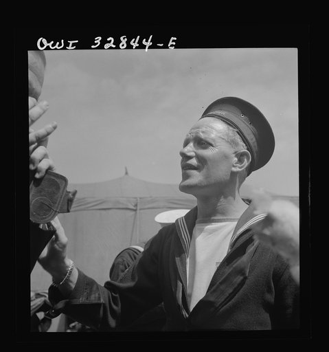 Untitled photo, possibly related to: Oswego, New York. A Belgian sailor giving sponge sugar to a little girl at the carnival during United Nations week