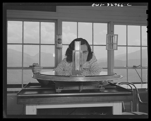 Gorham (vicinity), New Hampshire. Barbara Mortensen, a fire and airplane lookout on Pine Mountain, sighting suspicious smoke through a fire finder so as to locate accurately its source by cross bearings on the topographical chart