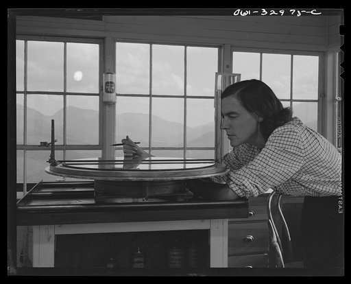 Gorham (vicinity), New Hampshire. Barbara Mortensen, a fire and airplane lookout on Pine Mountain, sighting through the fire finder which accurately locates fires on topographical maps
