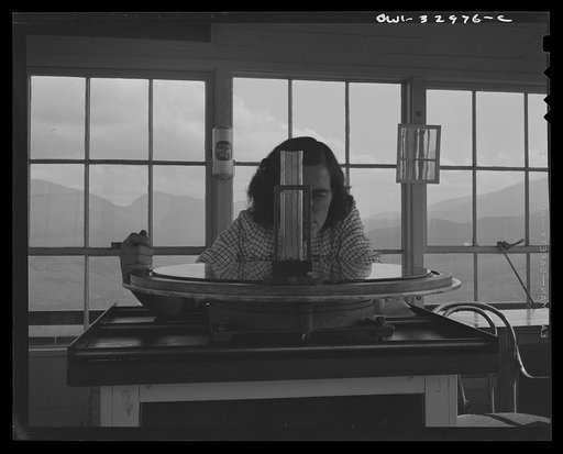 Untitled photo, possibly related to: Gorham (vicinity), New Hampshire. Barbara Mortensen, a fire and airplane lookout on Pine Mountain, sighting suspicious smoke through a fire finder so as to locate accurately its source by cross bearings on the topographical chart