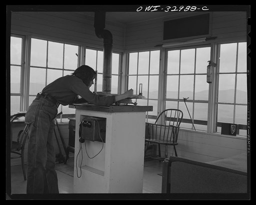 Gorham (vicinity), New Hampshire. Barbara Mortensen, a fire and airplane lookout on Pine Mountain sighting through the fire finder which accurately locates fires on topographical maps