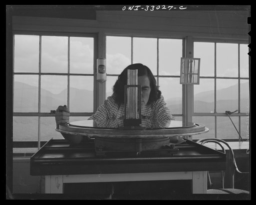 Untitled photo, possibly related to: Gorham (vicinity), New Hampshire. Barbara Mortensen, a fire and airplane lookout on Pine Mountain, sighting suspicious smoke through a fire finder so as to locate accurately its source by cross bearings on the topographical chart